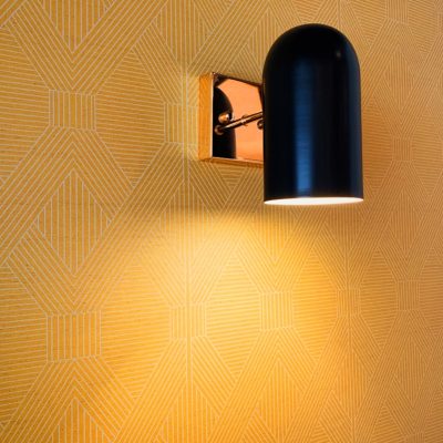 a black lamp on a wall next to a yellow wall